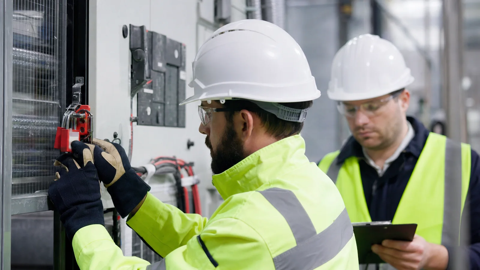 A technician applying lockout equipment while a supervisor independently verifies the energy-isolation control.